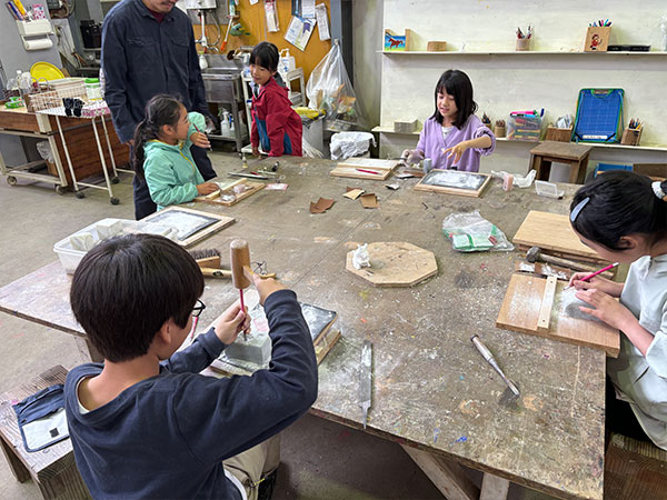大きな机を子どもたちが囲み図工の授業をしている